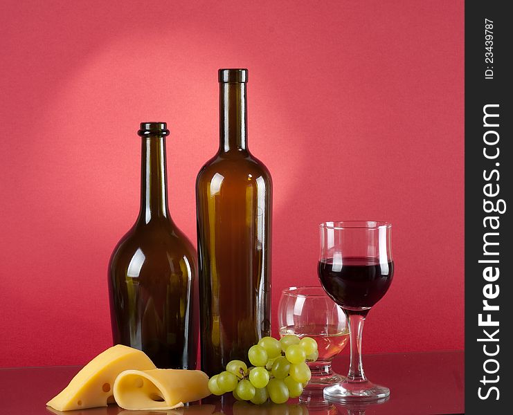 Glass and bottle of red wine over dark red background