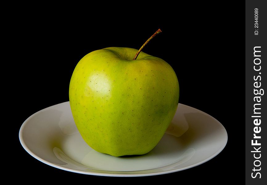 Photo of green apple on a plate on a dark background