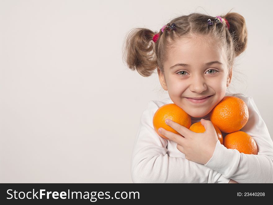 Little girl holding many oranges
