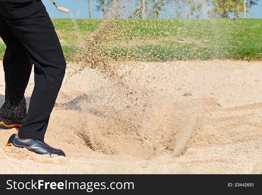 A professional golfer playing a shot out of a sand-trap. A professional golfer playing a shot out of a sand-trap