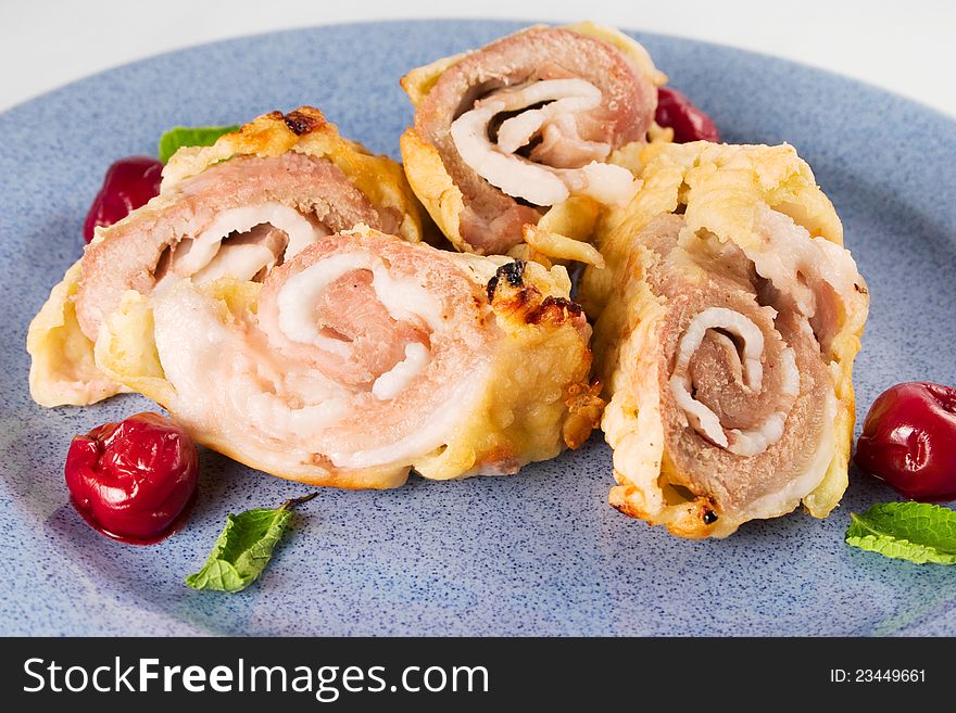 Baked pork rolls in puff pastry with cherry on blue plate. Baked pork rolls in puff pastry with cherry on blue plate