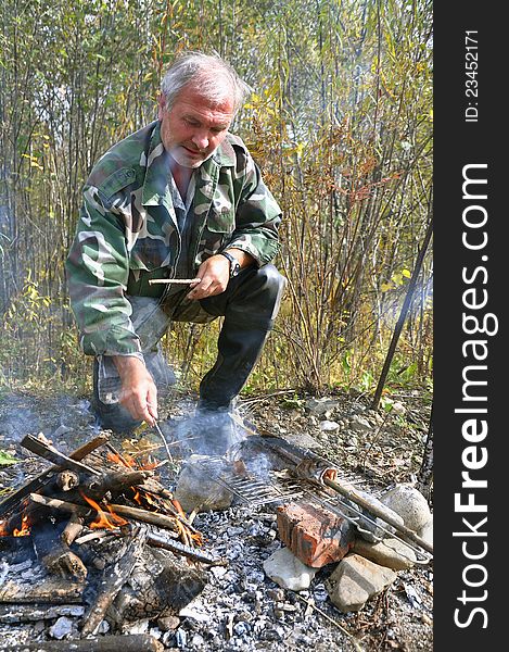 Fisherman by the fire roasting fresh fish