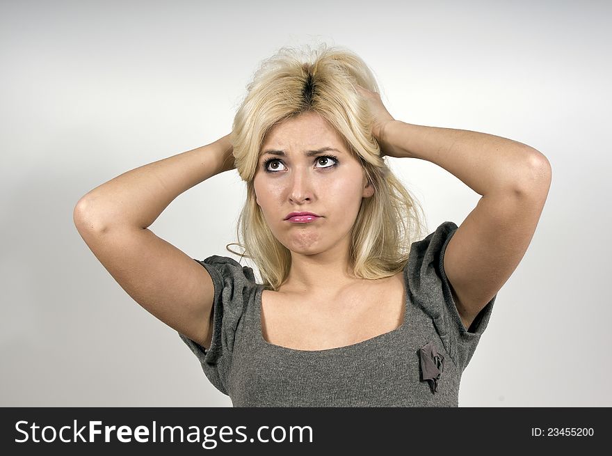 Beautiful girl upset looks up at the grey background