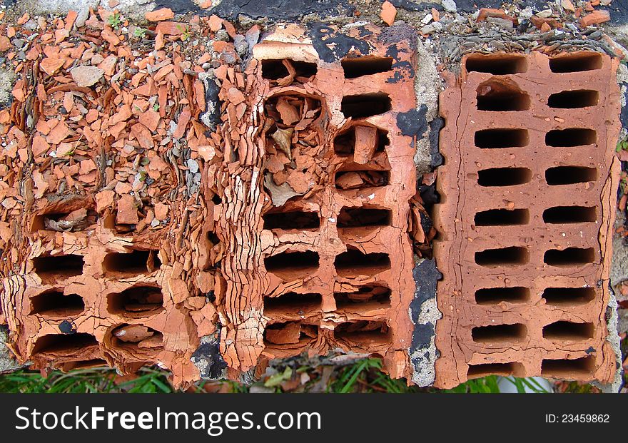 Three old red bricks crumble and fall