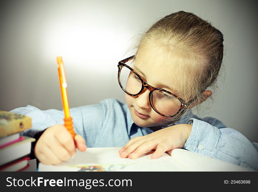 Schoolgirl with big glasses writes in a notebook. Schoolgirl with big glasses writes in a notebook