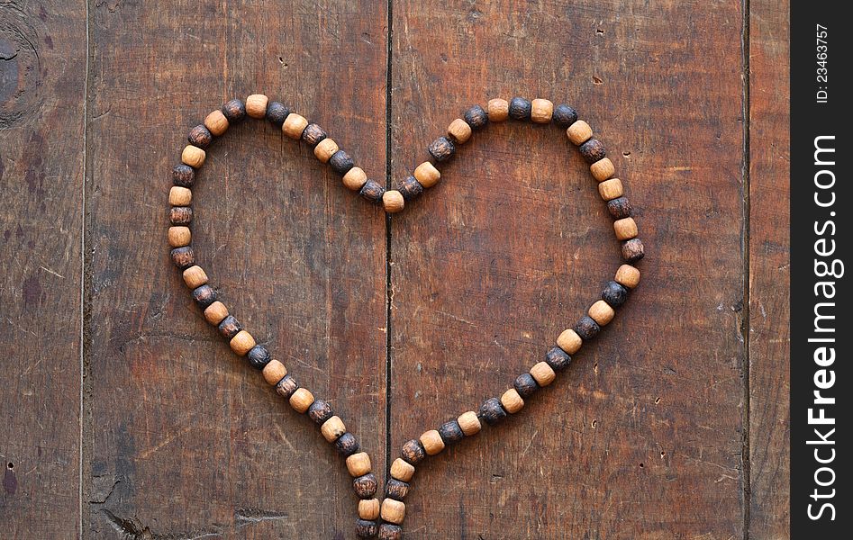 Costume Jewelry. Heart shape made from wooden necklace on wood surface. Costume Jewelry. Heart shape made from wooden necklace on wood surface