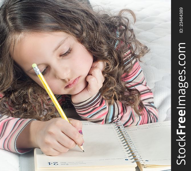 Little girl with notebook and pen in bed