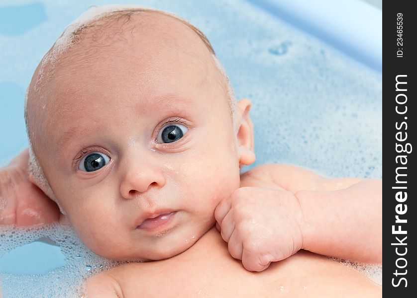 Newborn baby bathing in bathtub in hands