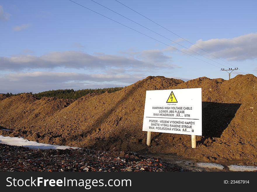 Warning sign standing near an excavation and warning about low voltage cables