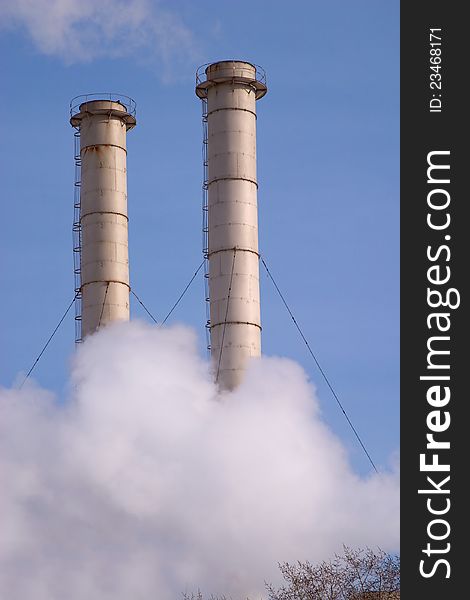 Industrial smoke pipes and white steam over blue sky. Industrial smoke pipes and white steam over blue sky