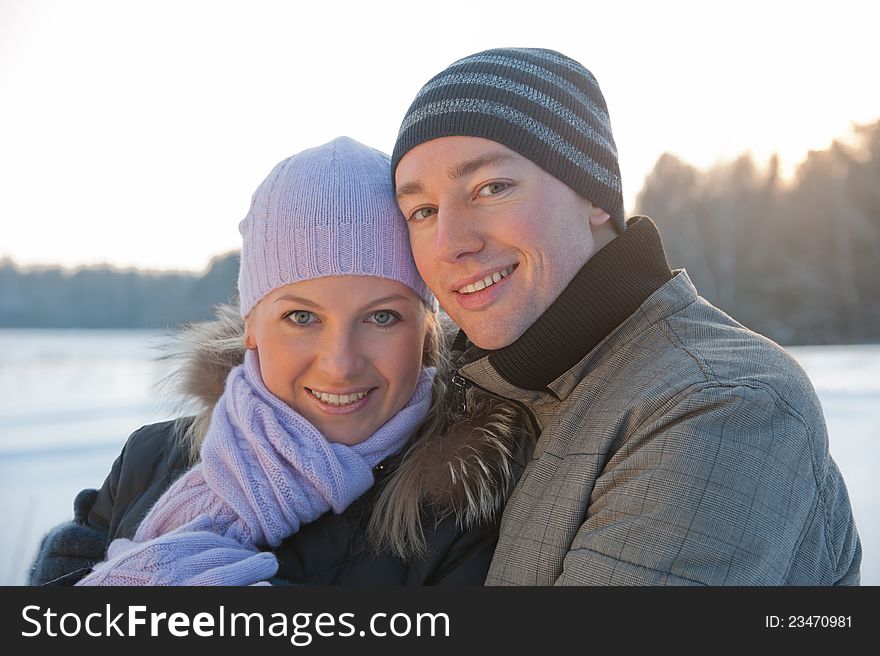 Smiling men and women at the sunlight on the winter background. Smiling men and women at the sunlight on the winter background