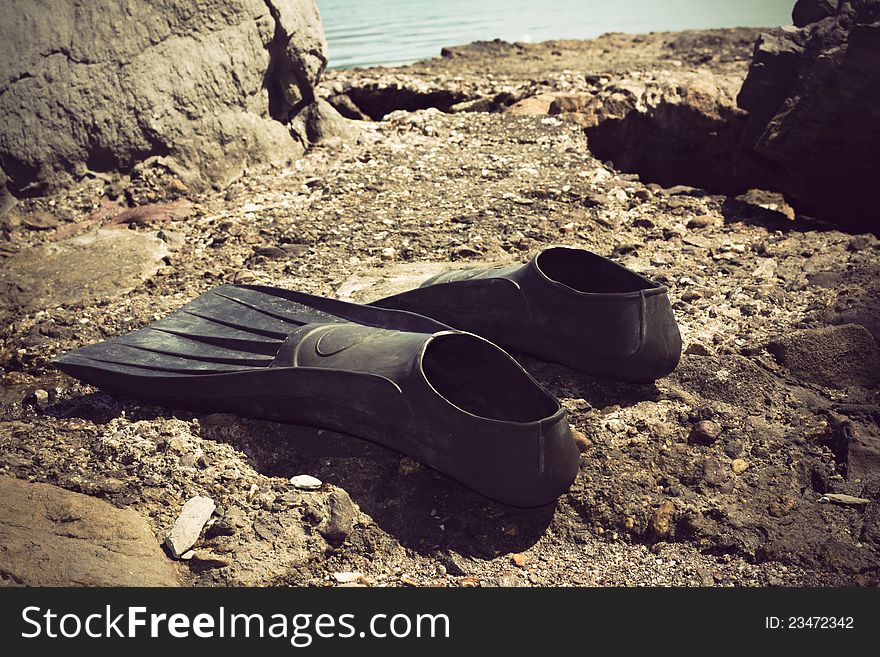 Vintage photo of black flippers on a rocky beach. Vintage photo of black flippers on a rocky beach