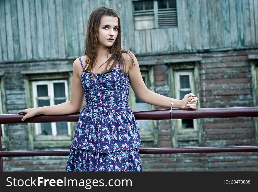 A girl stands near the old wooden house. A girl stands near the old wooden house