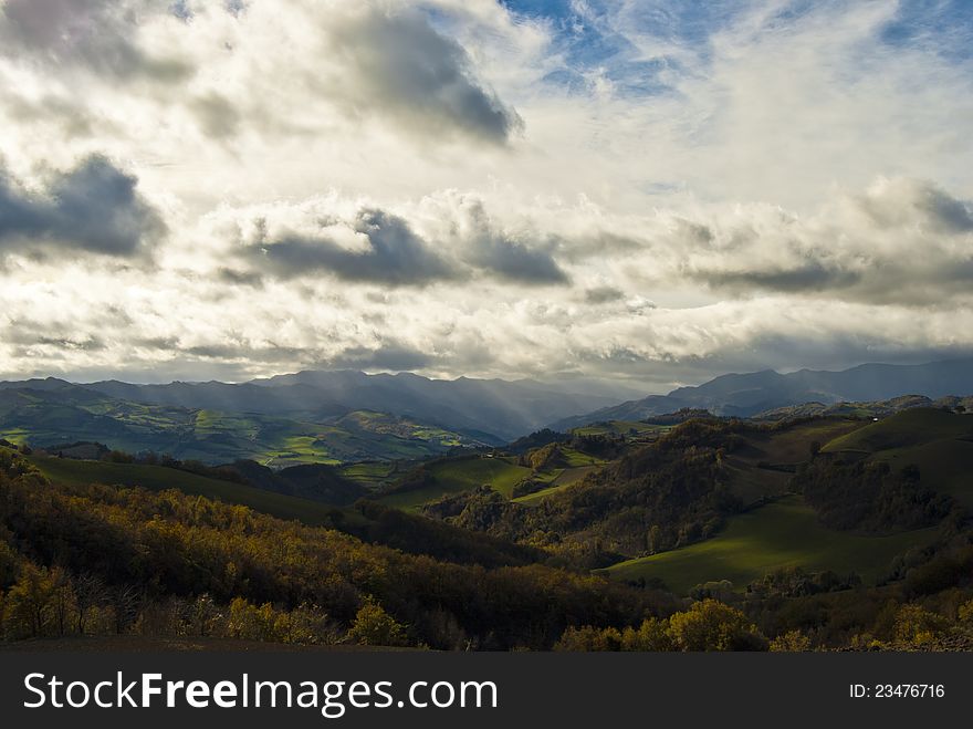 The sun tries to breach the clouds in a sunny Italian hills valley. The sun tries to breach the clouds in a sunny Italian hills valley