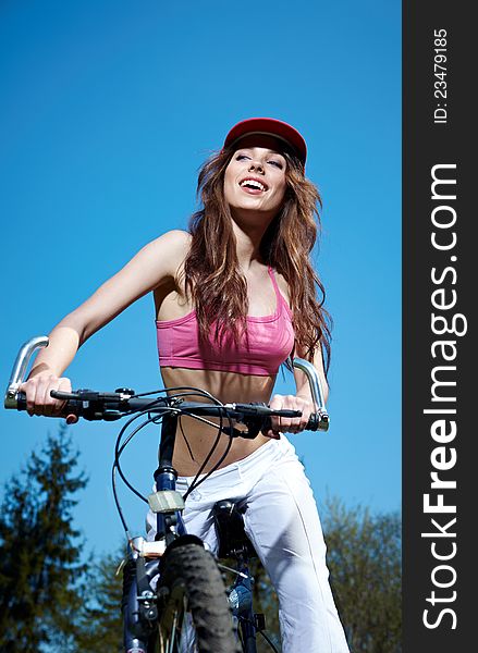 Young woman on a bicykle outdoors smiling