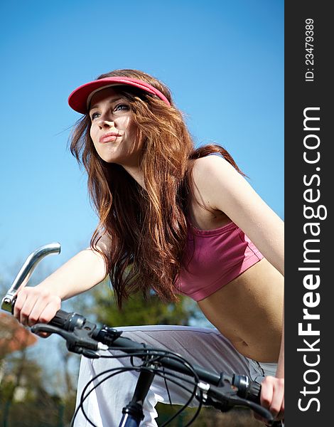 Young woman on a bicykle outdoors smiling