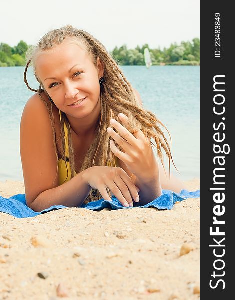 Beautiful girl with dreadlocks sunbathing on the beach