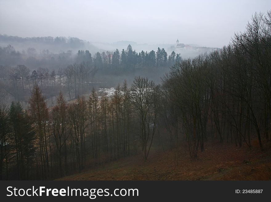 Hilly landscape in overcast day, city ​​on a hill in the background misty. Hilly landscape in overcast day, city ​​on a hill in the background misty