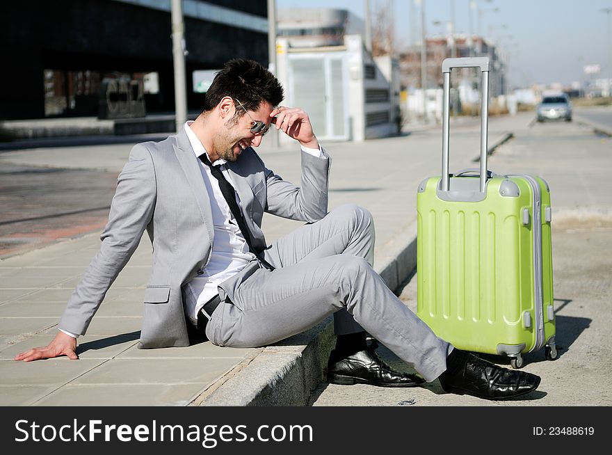 Man dressed in suit and suitcase sitting on the floor in the street. Man dressed in suit and suitcase sitting on the floor in the street