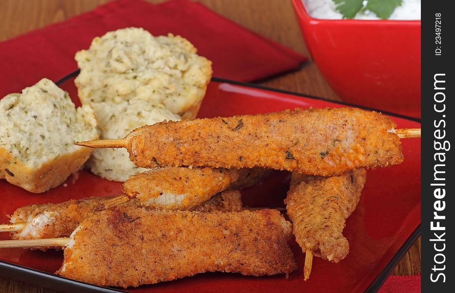 Chicken strip skewers with biscuits on a plate. Chicken strip skewers with biscuits on a plate