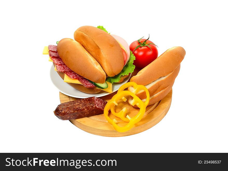 Sandwich with sausage and vegetables on plate, bread and vegetables on cutting board isolated on white background. Sandwich with sausage and vegetables on plate, bread and vegetables on cutting board isolated on white background