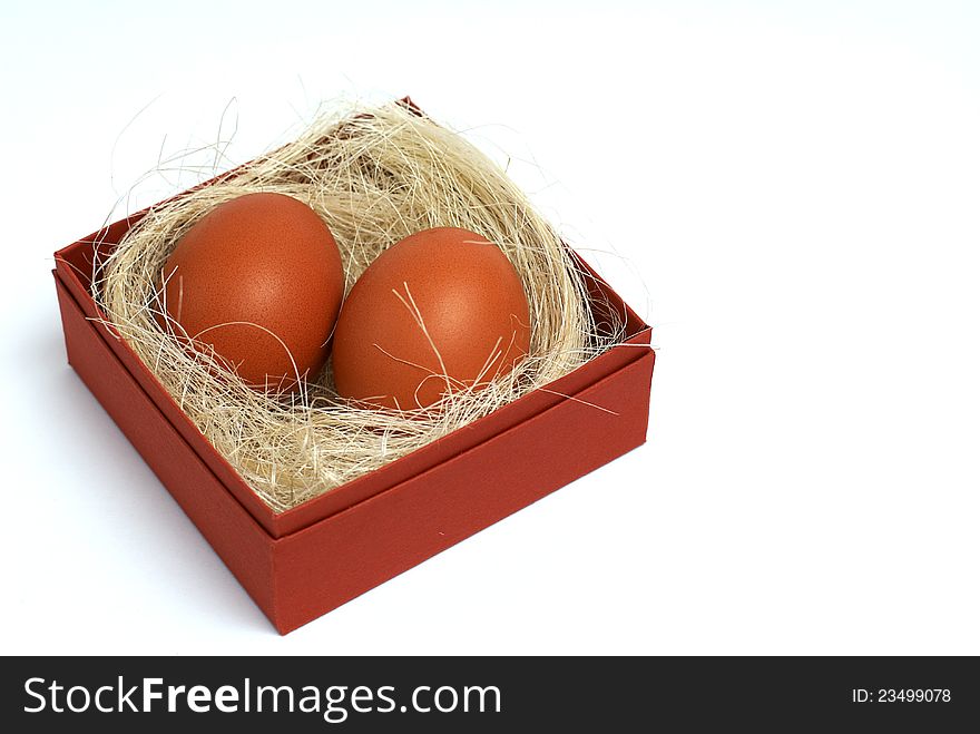 Two fresh brown eggs and some straw in a brown cardboard box on a white background. Two fresh brown eggs and some straw in a brown cardboard box on a white background