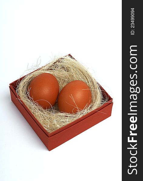 Two fresh brown eggs and some straw in a brown cardboard box on a white background. Two fresh brown eggs and some straw in a brown cardboard box on a white background