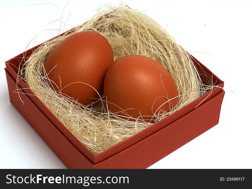 Two fresh brown eggs and some straw in a brown cardboard box on a white background. Two fresh brown eggs and some straw in a brown cardboard box on a white background