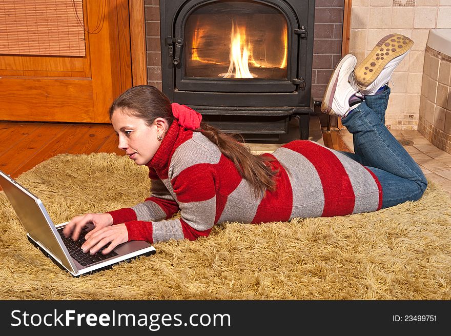 Girl with laptop lying on the carpet near the fireplace, and heated. Girl with laptop lying on the carpet near the fireplace, and heated