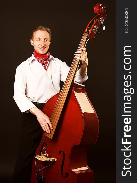Musician with contrabass. Over black background.
