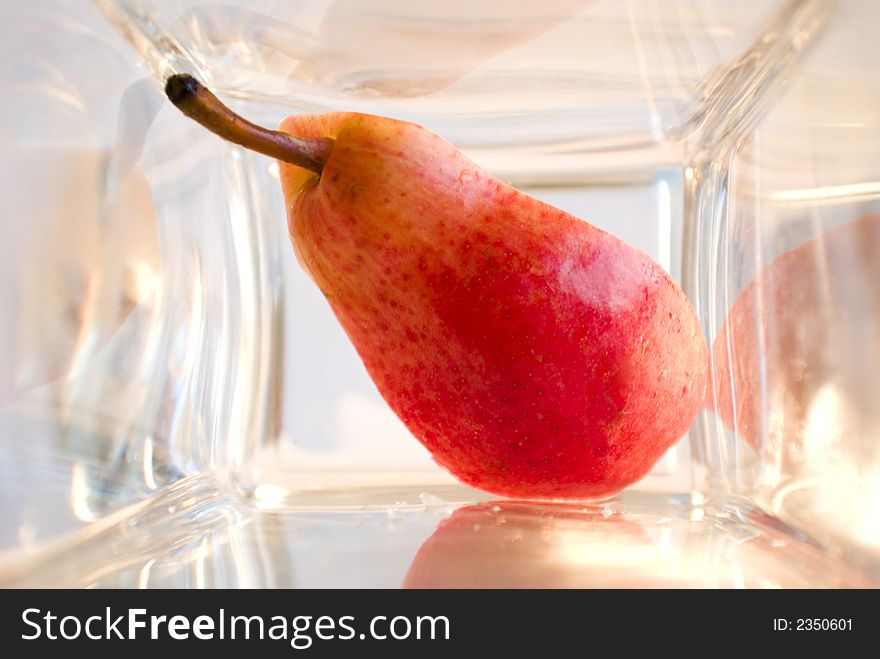 A bit of red ripe pear in a glass box. A bit of red ripe pear in a glass box