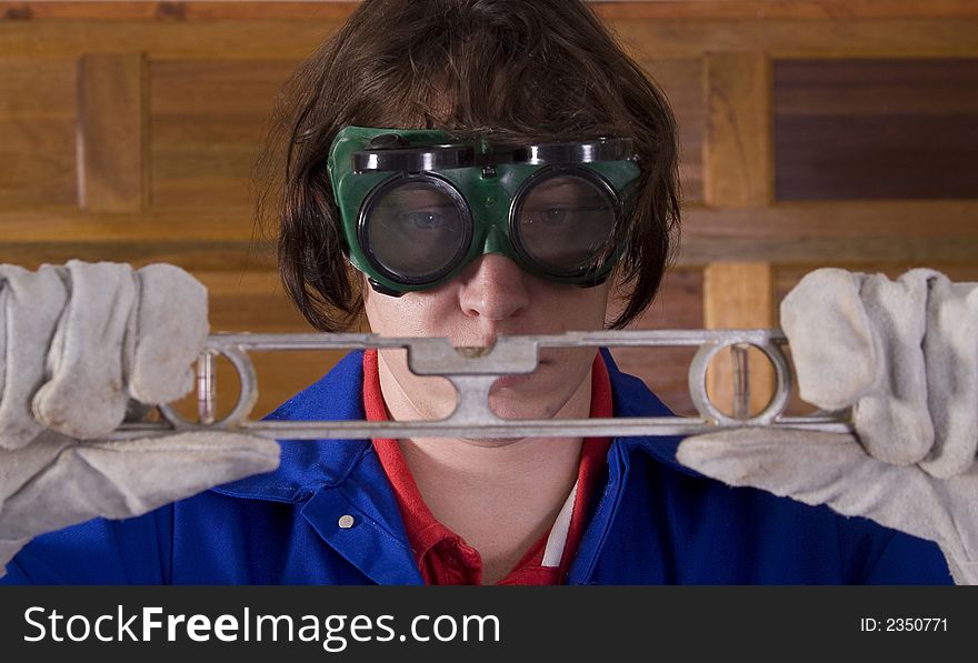 Handyman wearing goggles looking at leveller with gloves. Handyman wearing goggles looking at leveller with gloves