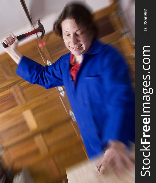 Dark haired man with blue overall holding hammer about to hit nail. Dark haired man with blue overall holding hammer about to hit nail