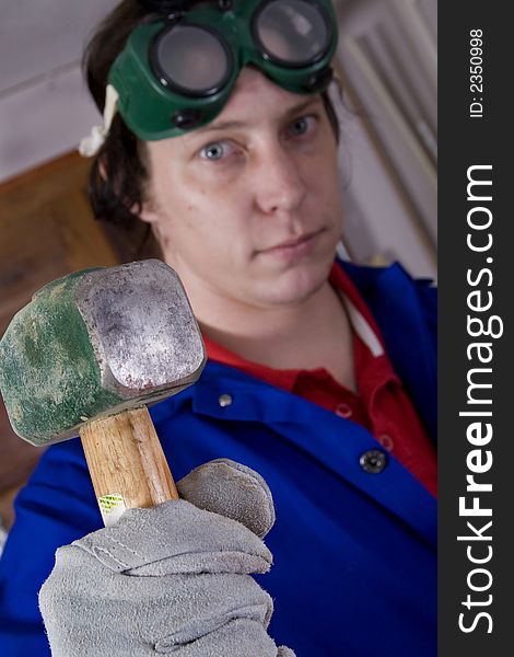 Dark haired man with blue overall holding hammer (focus on the hammer). Dark haired man with blue overall holding hammer (focus on the hammer)