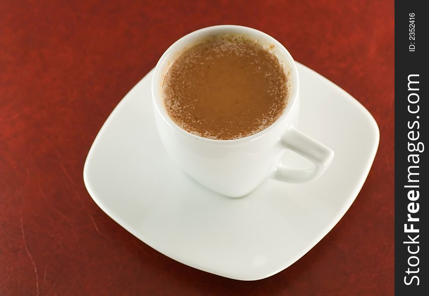 White cup of cappuccino on dark red background. White cup of cappuccino on dark red background