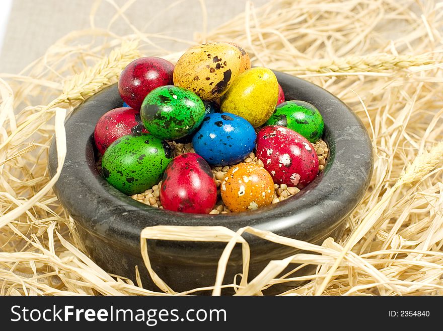Colorful eggs in bowl in straw