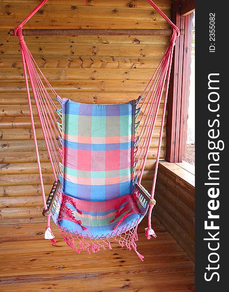 A colorful swing hanging on the porch of a wood cabin. A colorful swing hanging on the porch of a wood cabin