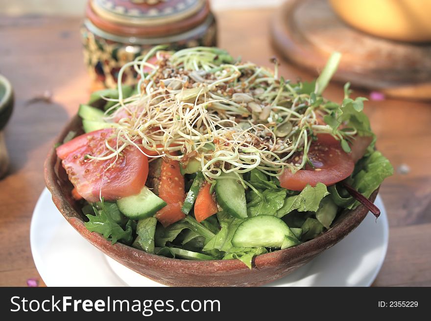 An organic vegetable salad in a clay bowl in natural light. An organic vegetable salad in a clay bowl in natural light