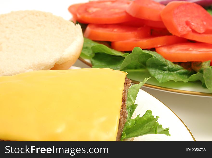 Cheeseburger withlettuce and tomato in background