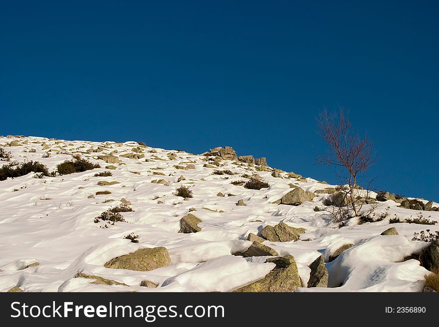 Snow covered mountain slope under blue sky. Snow covered mountain slope under blue sky