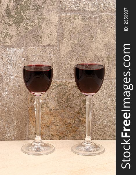 Two glasses of wine in dark stones wall background