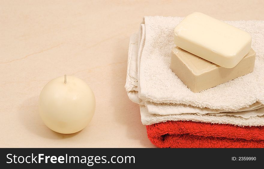 Red and white towels and honey soaps with candle in spa bathroom (spa concept )