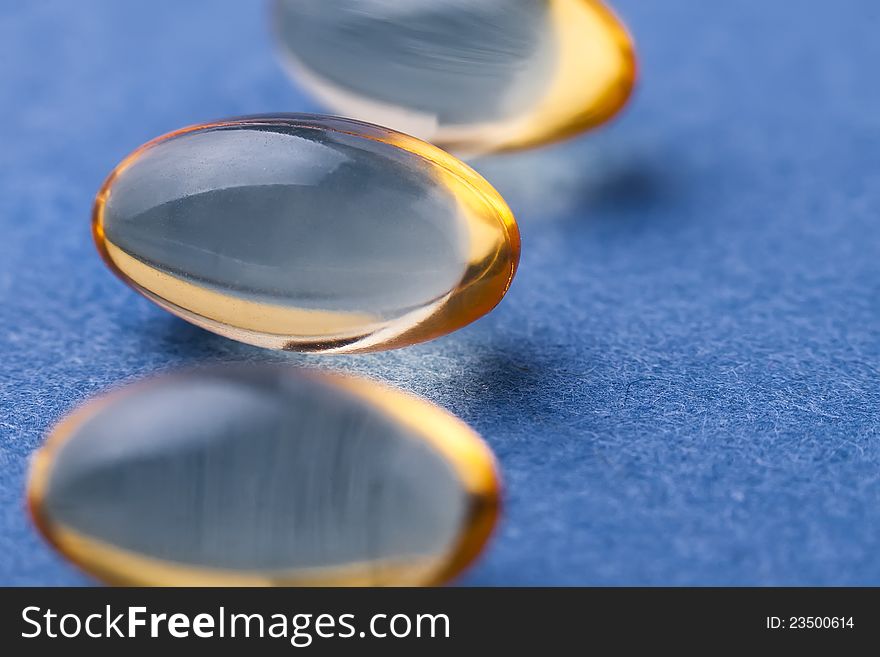 Transparent yellow pills against blue background