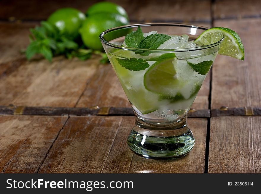 Fresh mojito in a lowball glass on a rustic table garnished with limes and mint leaves. Fresh mojito in a lowball glass on a rustic table garnished with limes and mint leaves.