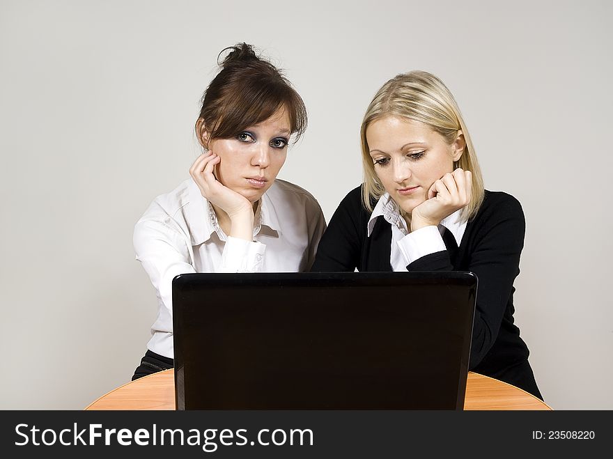 Beautiful girls upset look of the laptop at the table. Beautiful girls upset look of the laptop at the table