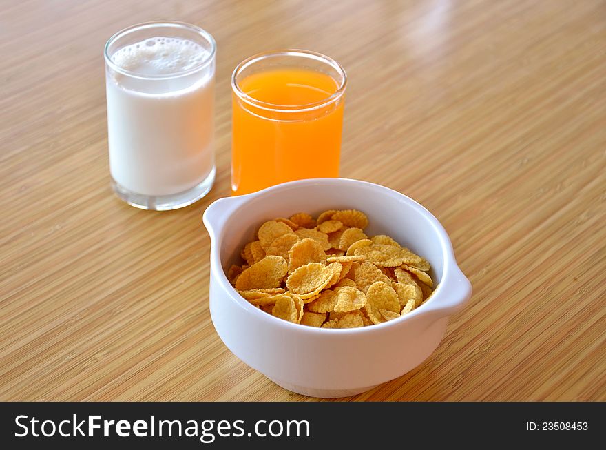 Delicious cornflaskes,  white  milk  and orange juice. Delicious cornflaskes,  white  milk  and orange juice