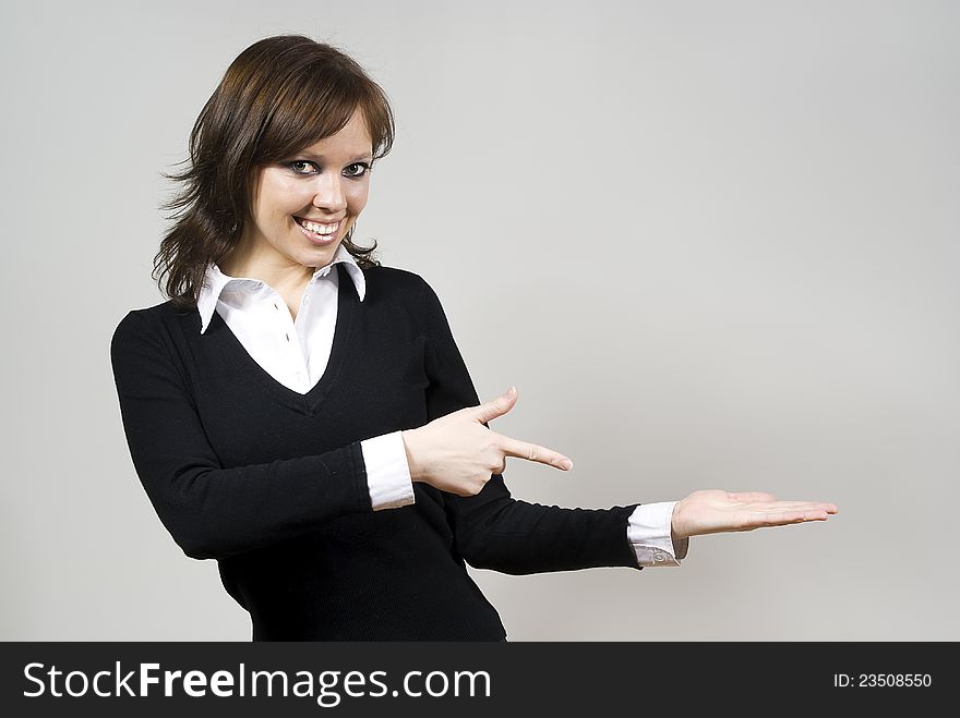 Beautiful girl smiling indicates standing finger on the palm of his hand on the background of. Beautiful girl smiling indicates standing finger on the palm of his hand on the background of