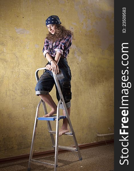 Girl standing on the ladder near unpainted wall