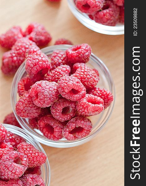 Bowl of raspberries on wooden table close up