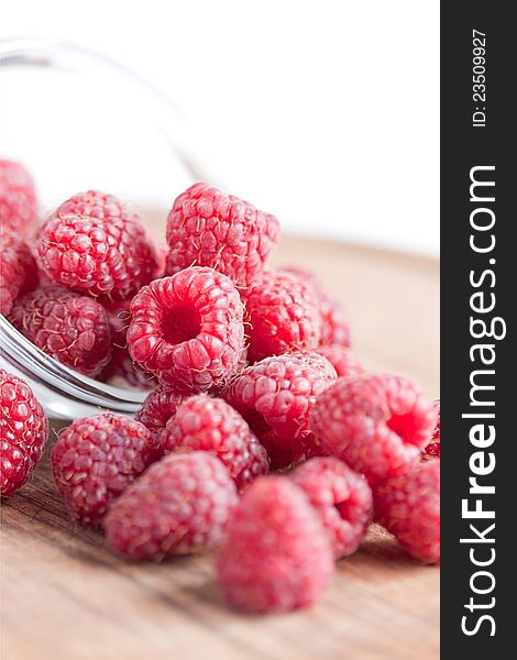Bowl of raspberries on wooden table close up